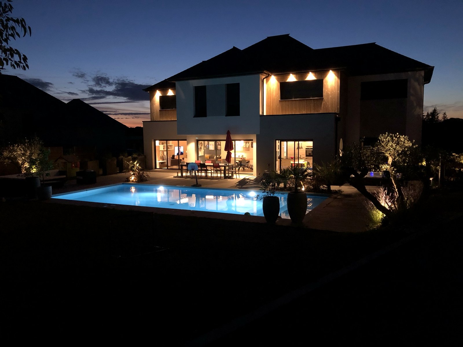 Façade nocturne illuminée et piscine — showroom LUMÆ